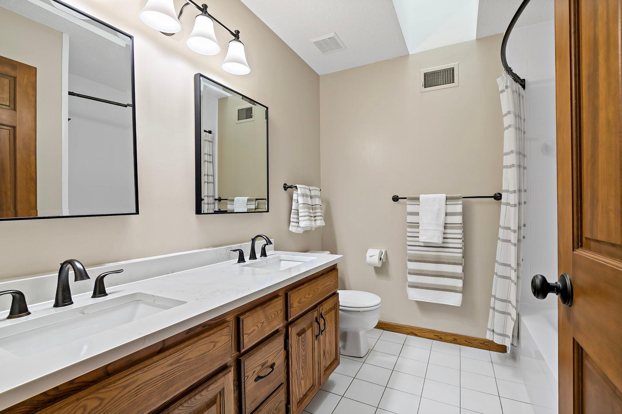 Upper level full bath with new quartz countertops and dual sinks, lighting mirrors and faucets.