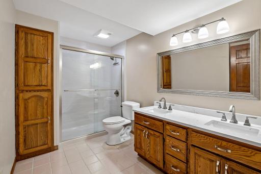The lower-level 3/4 bath features a new quartz countertop with dual sinks, new lighting, mirror, faucets, and upgraded shower.