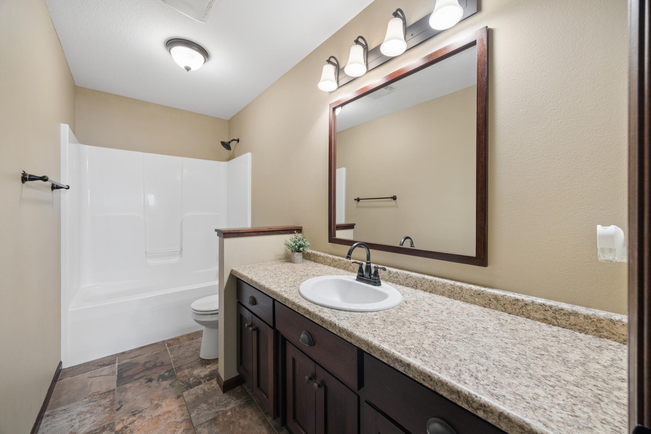 This upper level full bathroom has a large counter and bright lights