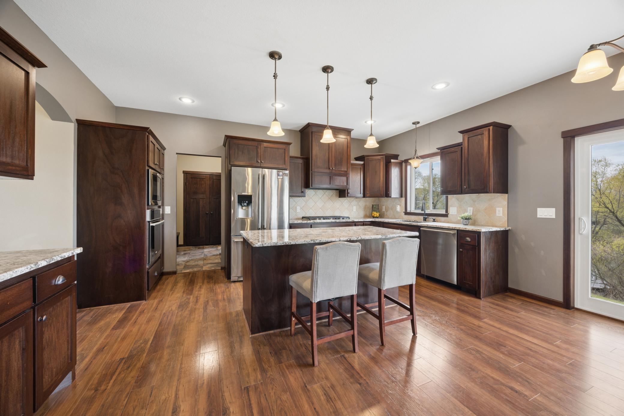 The heart of the home is the stunning kitchen, featuring a plethora of upgraded staggered dark mahogany cabinetry