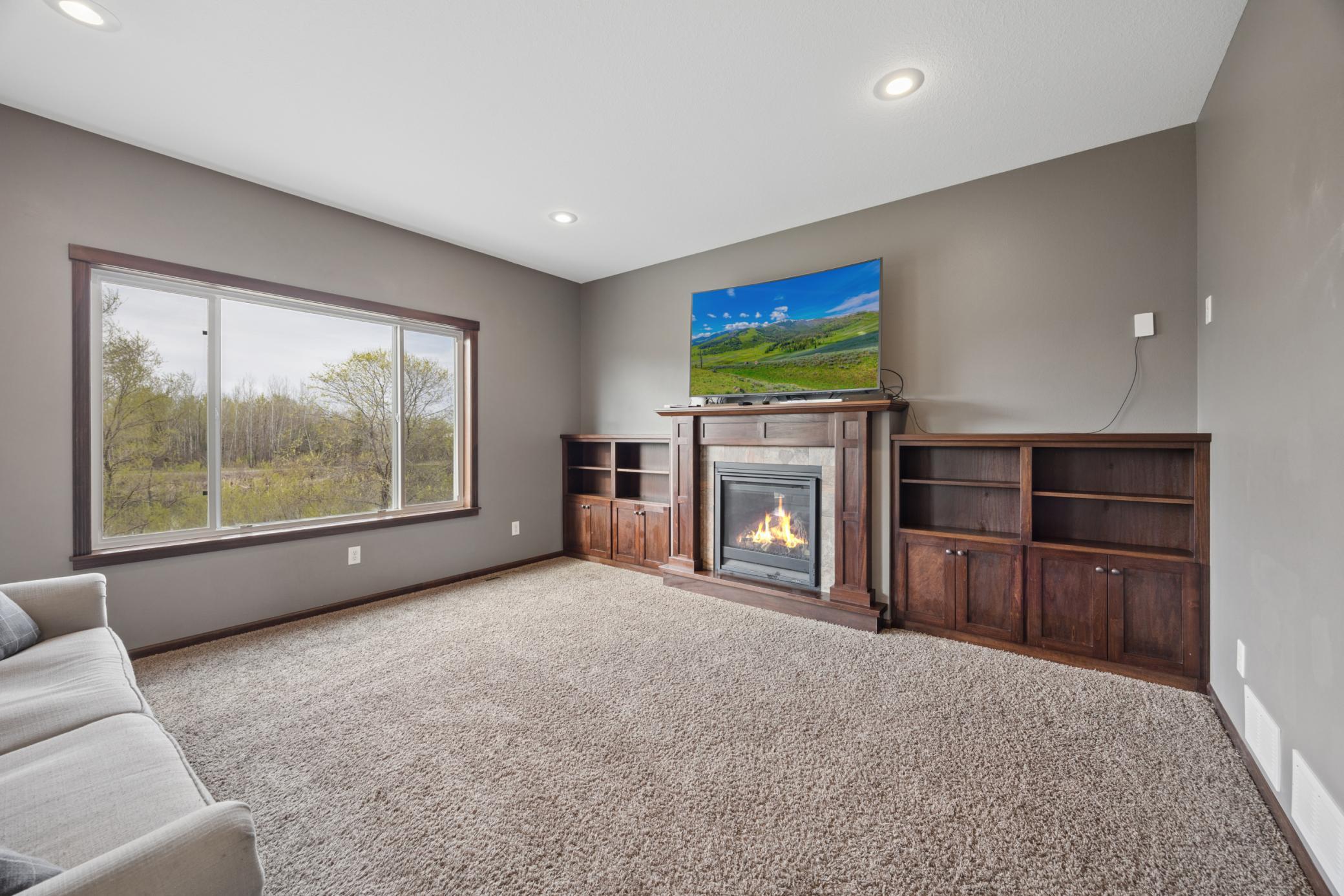 The living room is warm and inviting, anchored by a striking gas fireplace, flanked by custom built-in shelving and enhanced by recessed lighting
