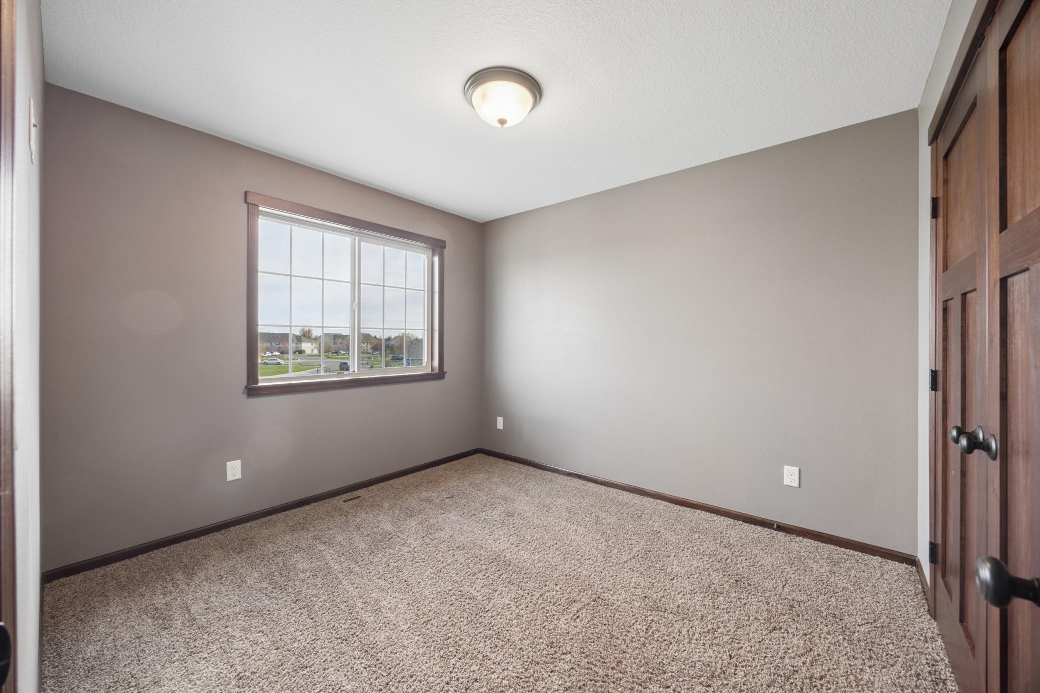 Another upper level bedroom also with plush carpet and a big window