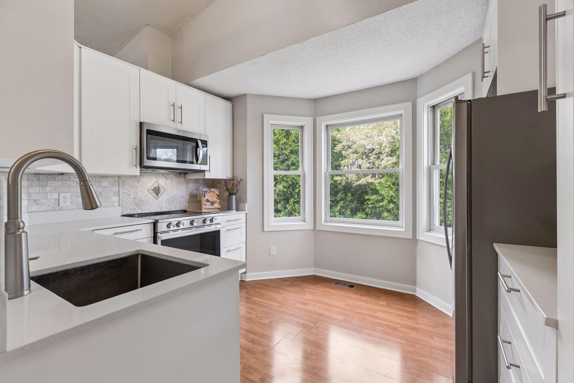 Pristine kitchen with stainless steel appliances with bay window allowing for informal dining