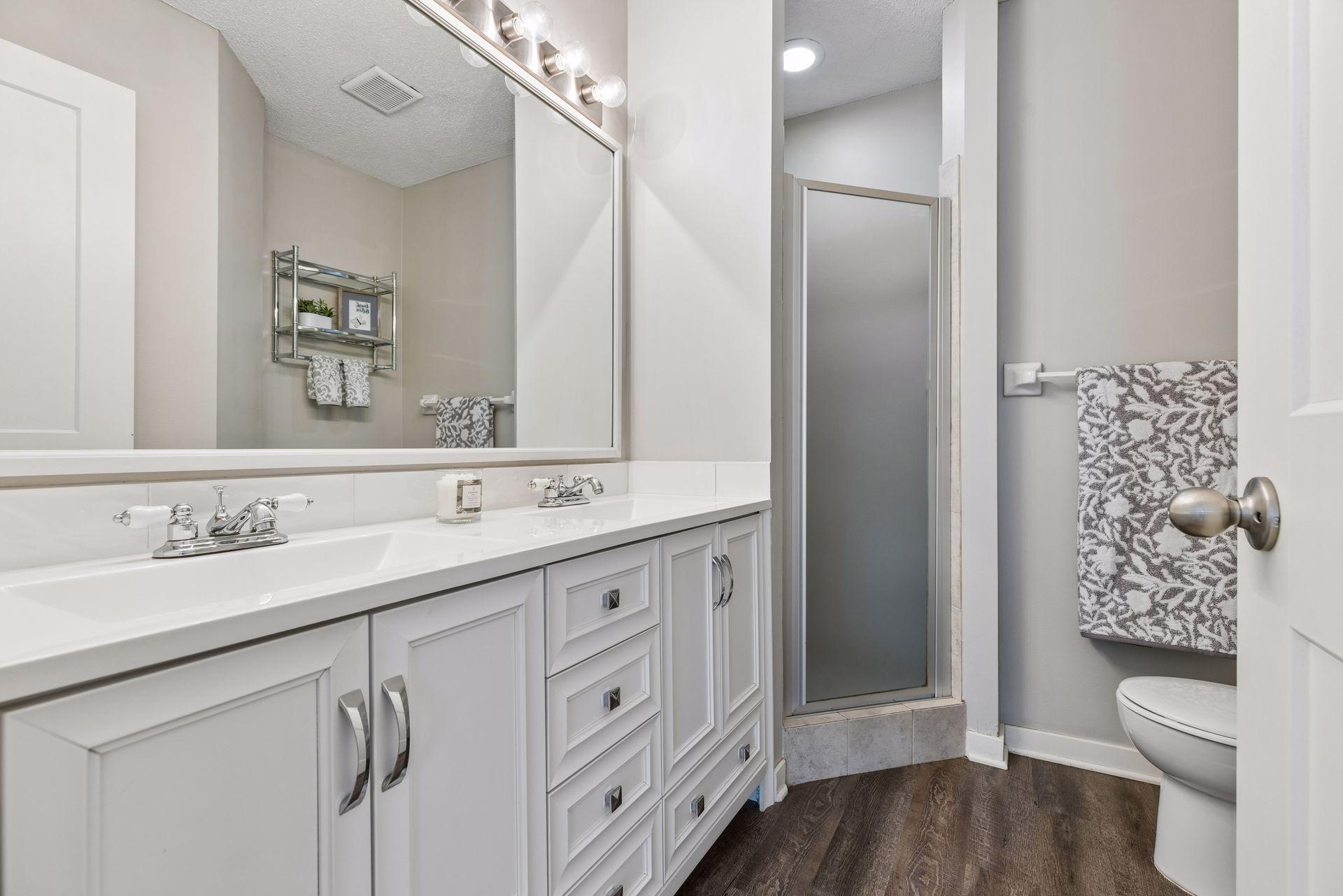 3/4 Primary ensuite with luxury wood plank flooring and tile surround shower along with dual sinks