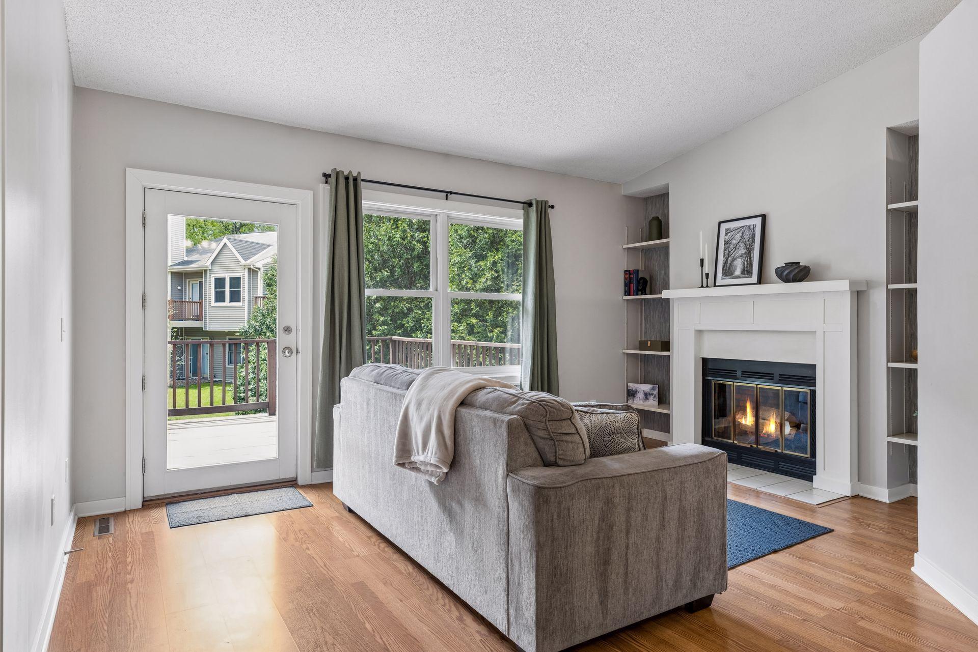Cozy living room with wood burning fireplace overlooks the private treed backyard