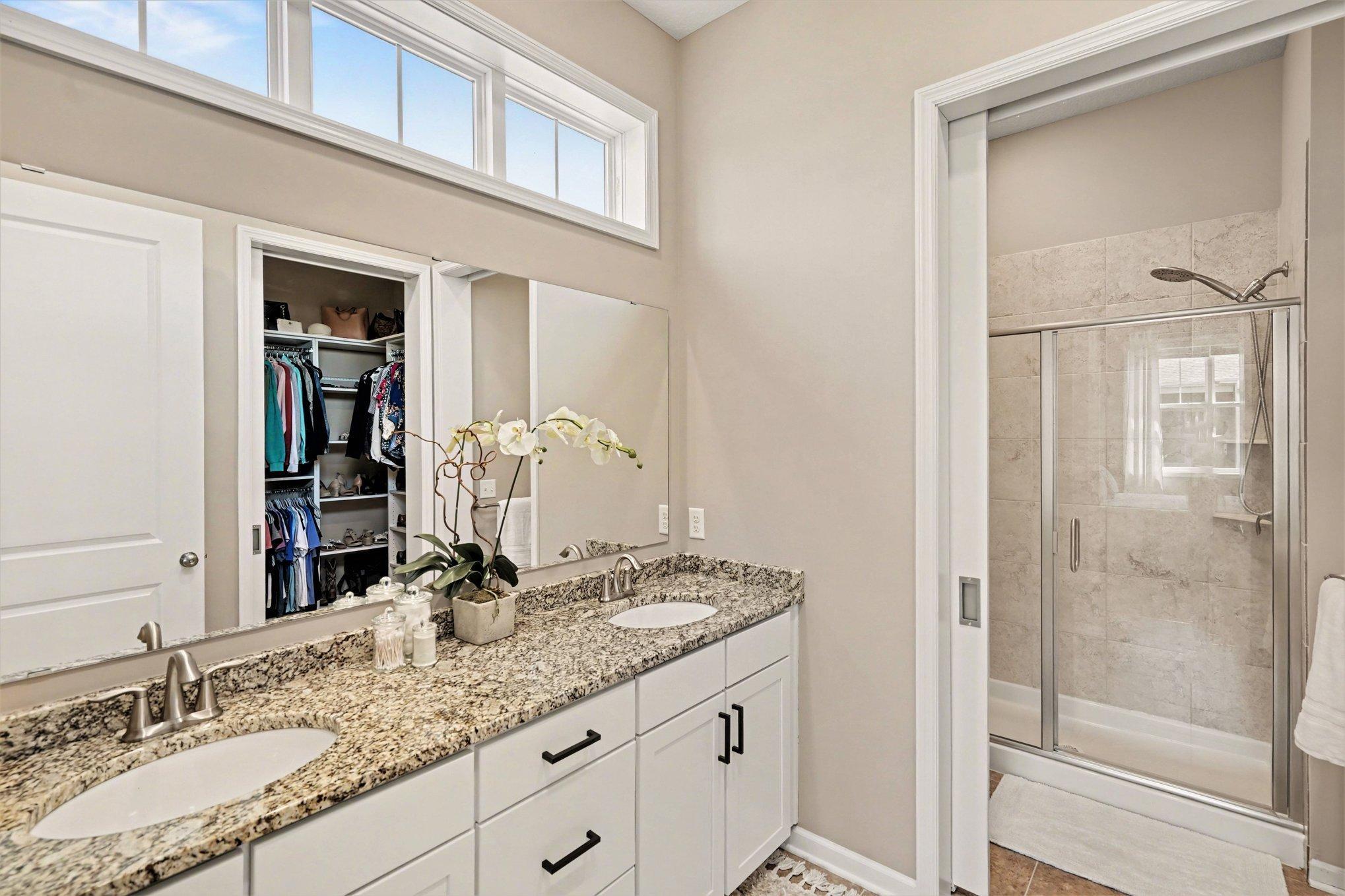 Double sinks, granite countertops and a large closet with a custom closet