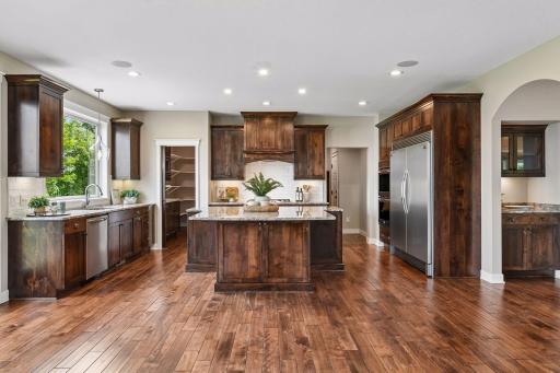 Beautifully appointed kitchen with expansive center island, granite surfaces, stainless appliances, double ovens, and rich alder cabinetry.