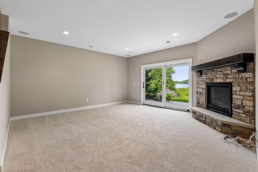 Lower level walkout family room with a 2nd stone-surround gas fireplace and direct access to the backyard patio.