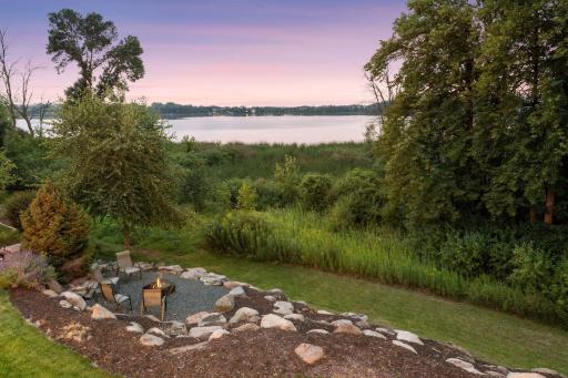 Landscaped backyard features a distinctive boulder feature and firepit area surrounded by a naturalized setting.