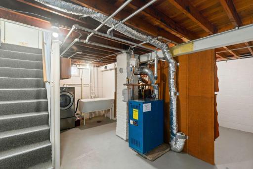 Spotless basement features clean and tidy laundry area and newer boiler