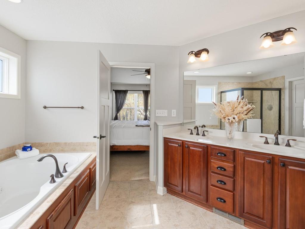 Primary Bath features dual sink vanity, jetted tub, and separate glass-enclosed shower.