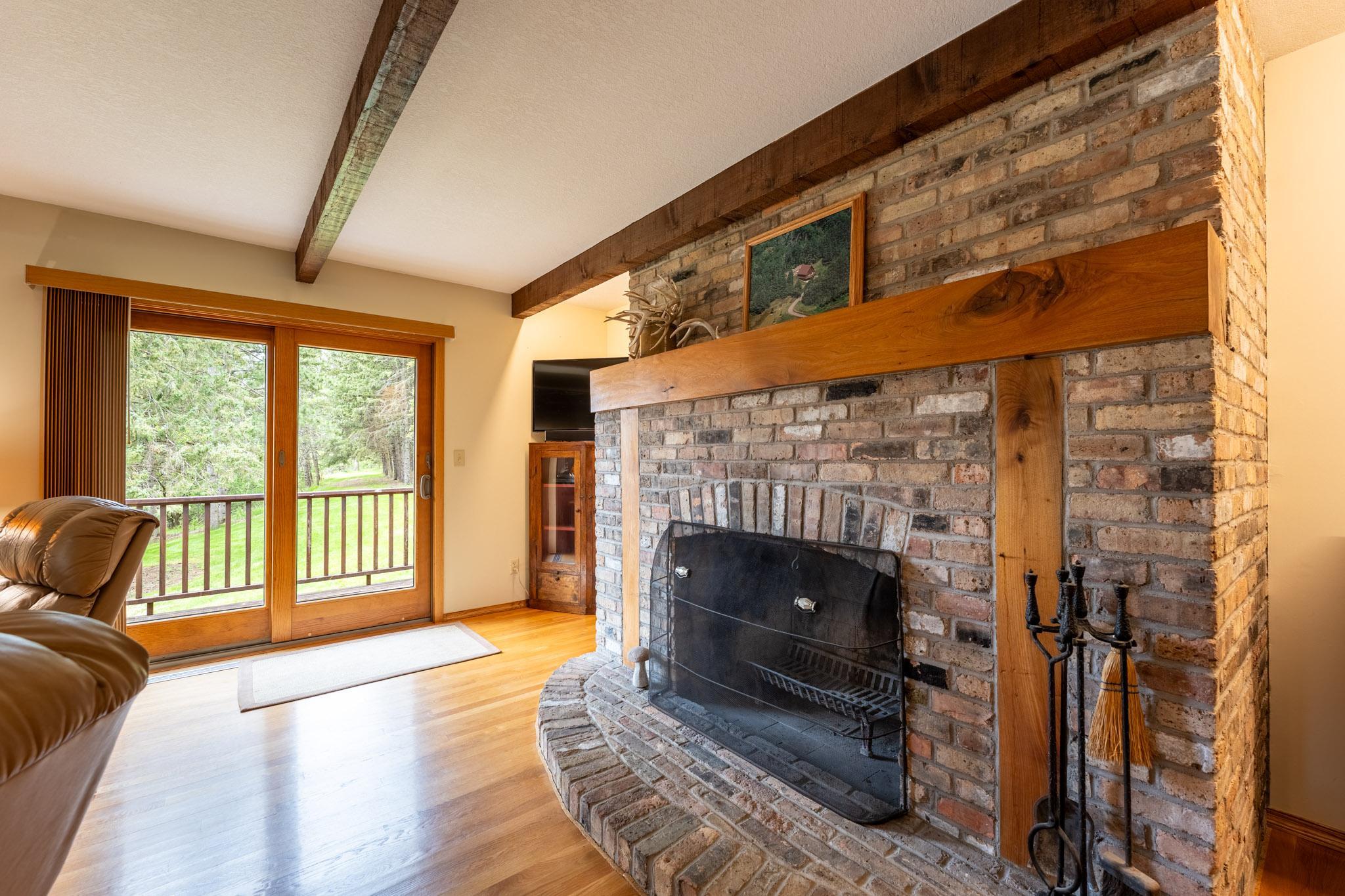 In the Living Room is a brick surround wood burning fireplace and Anderson sliding glass doors out to the wraparound deck.