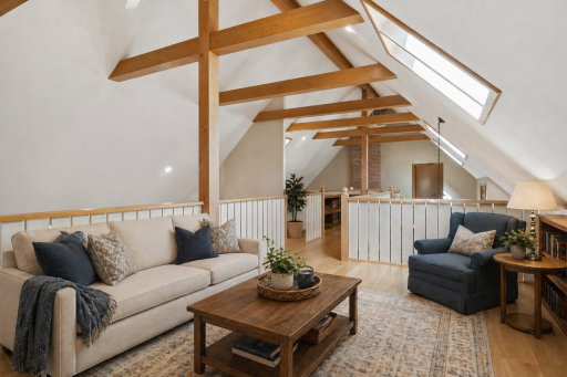 Dramatic loft living area showcasing vaulted ceilings, exposed beams, skylights, and open architectural design.This photo has been virtually staged.