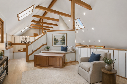Expansive upper-level loft with exposed wood beams, skylights, and flexible living space overlooking the main level below. This photo has been virtually staged.