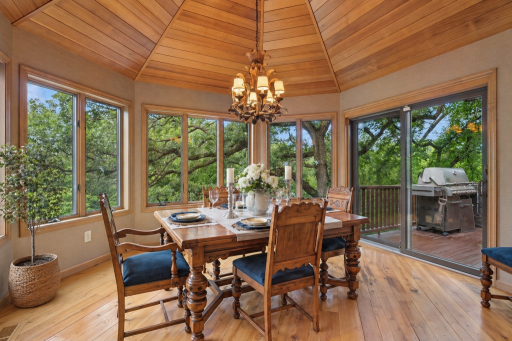 Sun-filled dining area featuring vaulted wood ceilings, panoramic wooded views, and direct access to the maintenance-free deck.