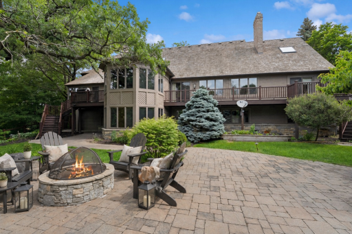 Private backyard retreat featuring a spacious paver patio, firepit gathering area, mature landscaping, and multiple outdoor entertaining spaces.