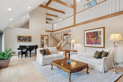 Open-concept formal living area with loft overlook, warm wood accents, and abundant natural light