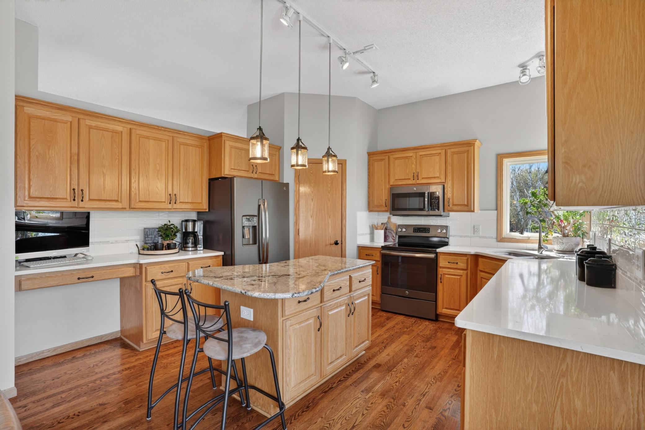 Kitchen featuring custom cabinetry, quartz countertops, and granite center island