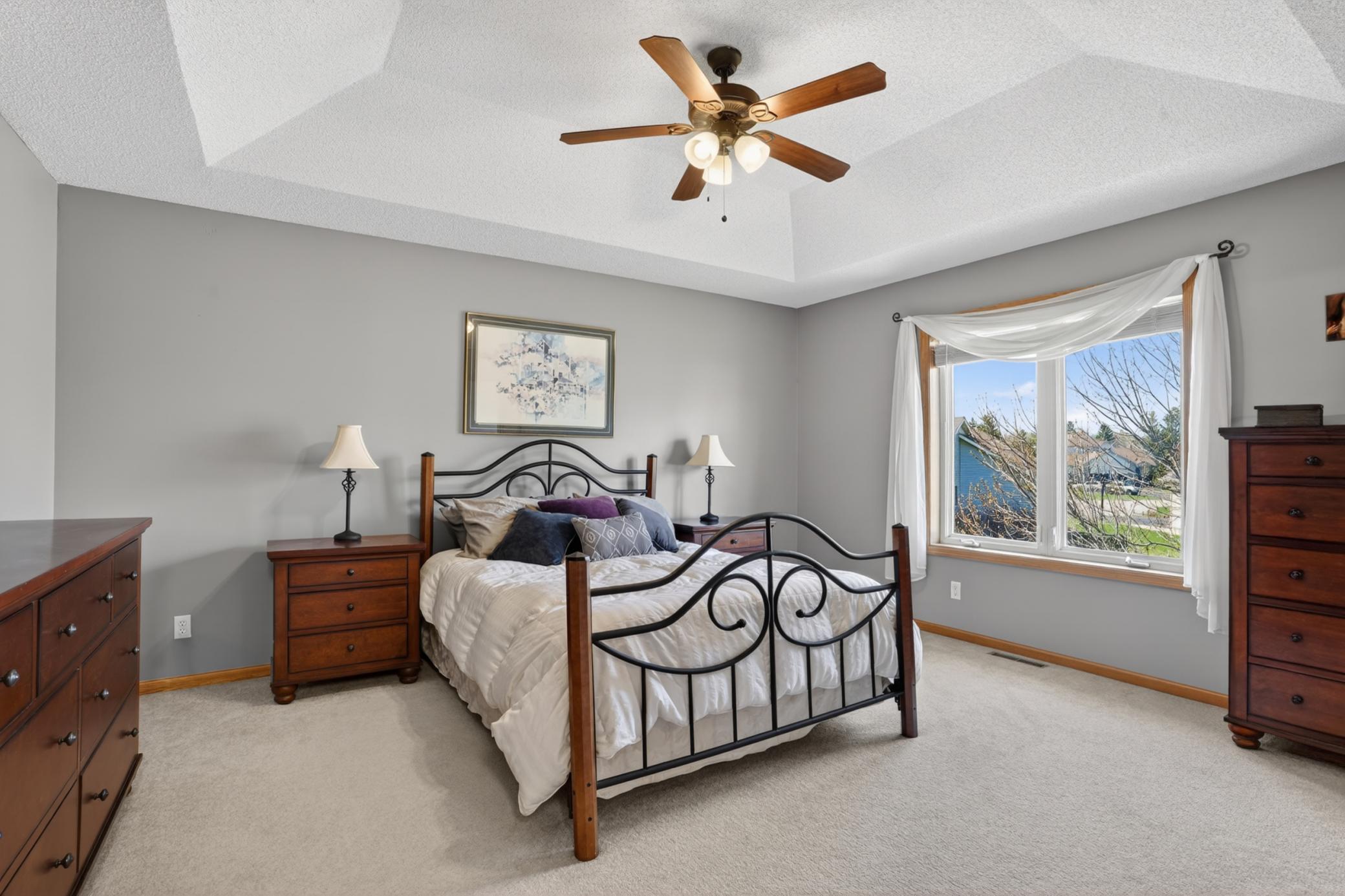 Private primary suite featuring tray ceiling, large windows, and spacious layout