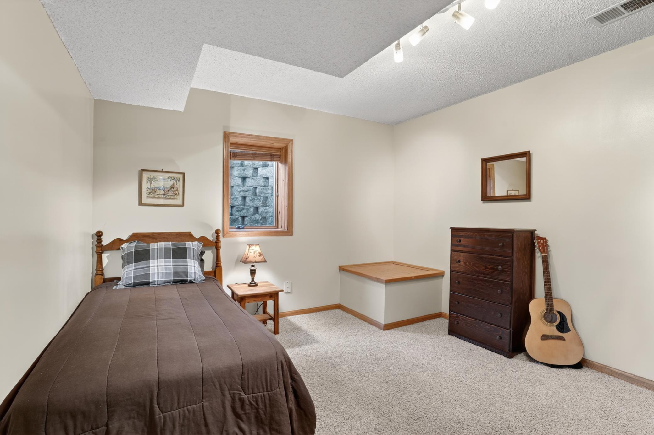 Comfortable lower-level guest bedroom with natural light and functional layout