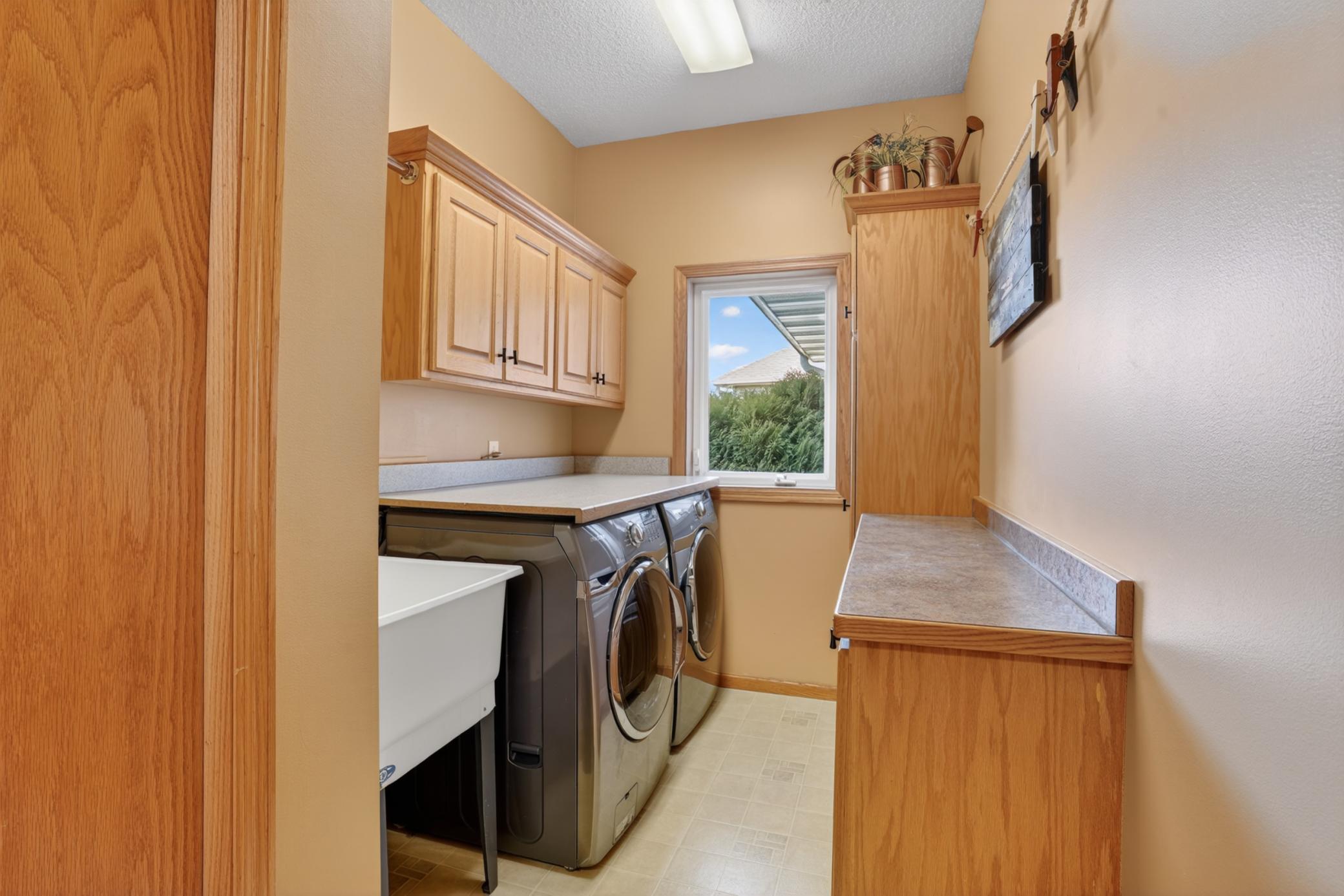 Main-floor laundry room with storage, utility sink, and functional workspace