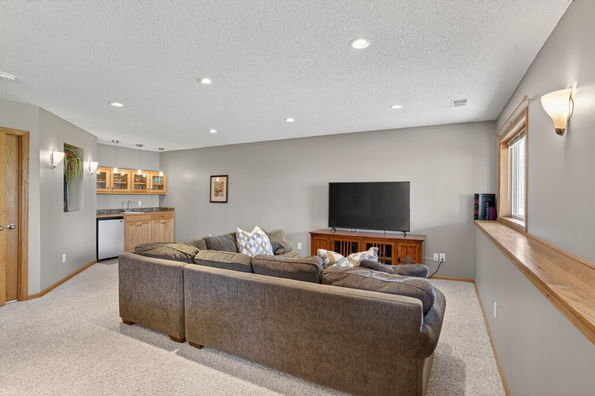Expansive lower-level family room with built-in wet bar area, perfect for entertaining