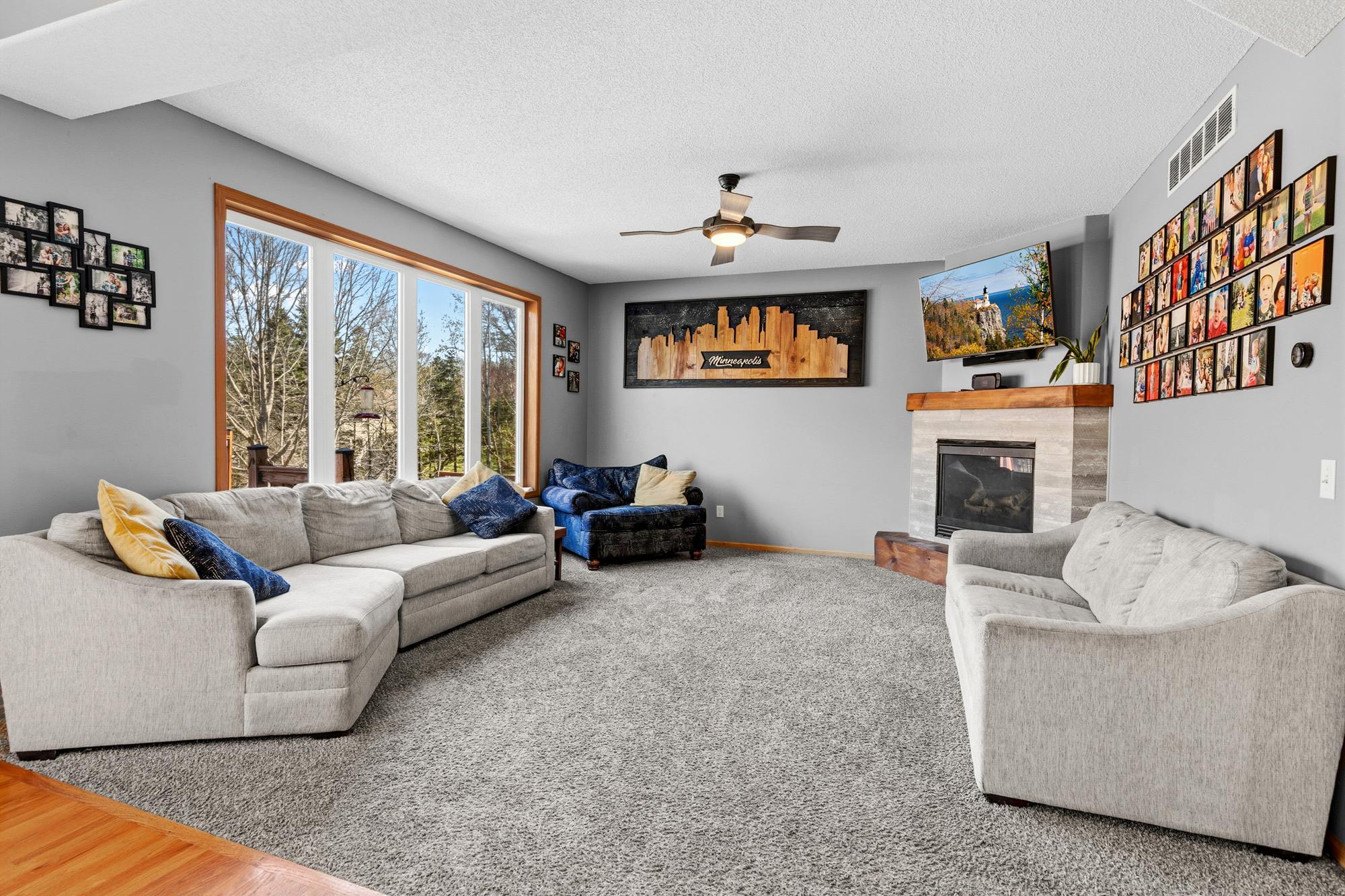 The wall of windows fills the Living Room with natural light. The fireplace completes the cozy atmosphere.