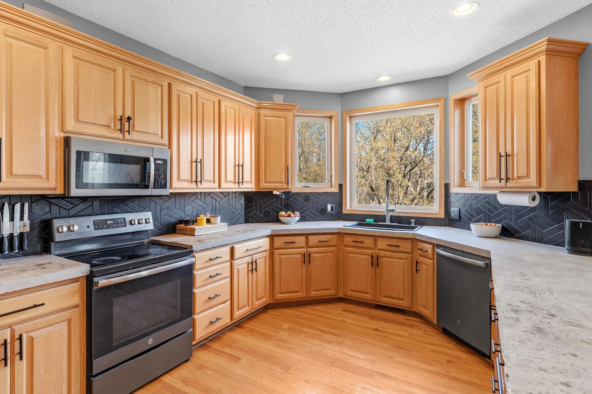 This Apple Valley home's elegantly updated Kitchen features a tile backsplash, custom cabinets, and concrete counters, new in 2020. A great space to prepare your meals, its functional and beautiful.