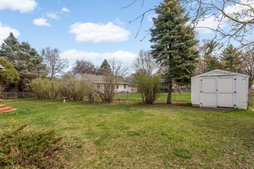 Large, fully fenced yard has a storage shed for additional toys.