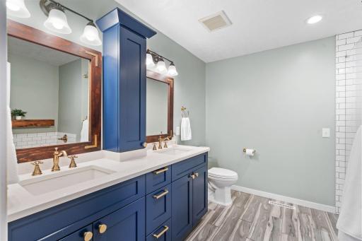 Beautifully updated primary bathroom featuring dual vanities, custom cabinetry, and elegant gold finishes.