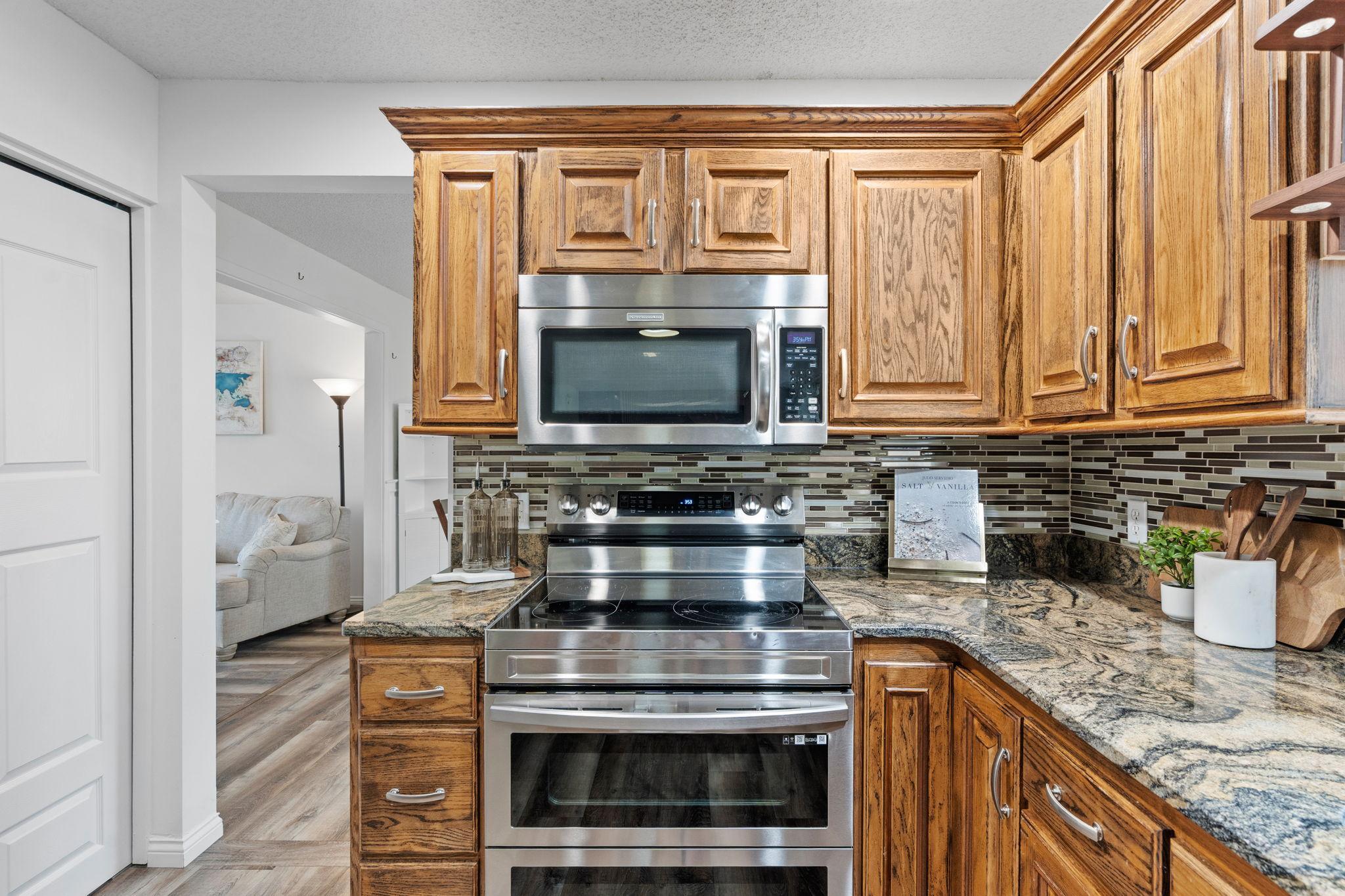 Stainless steel appliances, rich cabinetry, and detailed backsplash bring timeless character to the heart of the home.