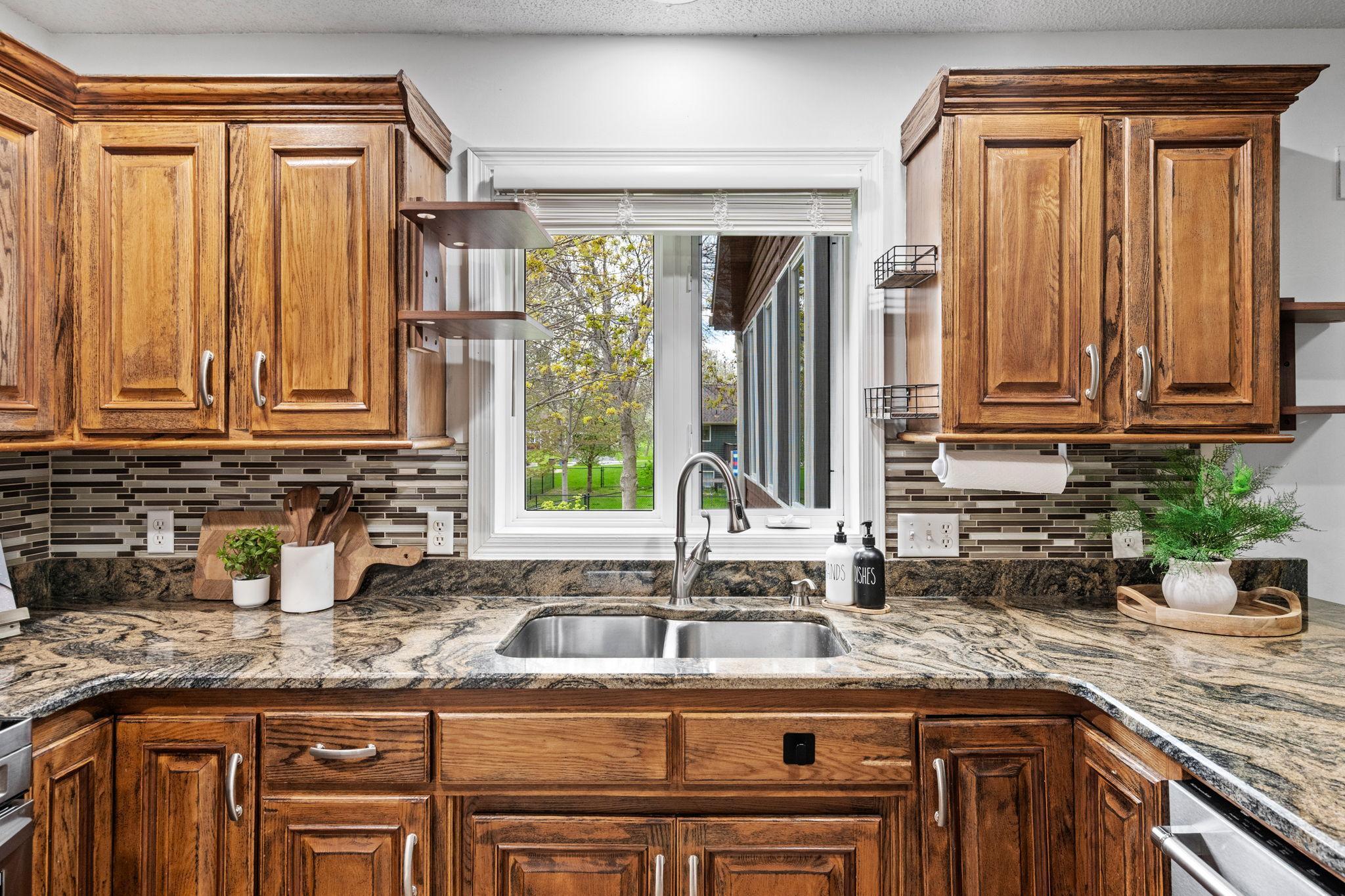 Large window over the sink fills the kitchen with natural light while showcasing the beautiful granite surfaces and generous workspace.
