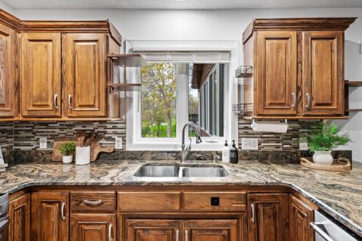 Large window over the sink fills the kitchen with natural light while showcasing the beautiful granite surfaces and generous workspace.