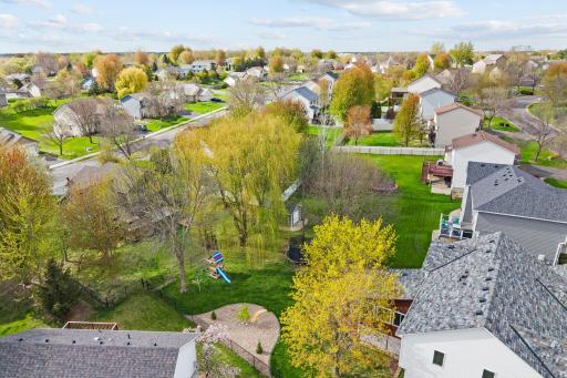 Fully fenced yard with beautiful mature trees, play space, and a patio ready for summer gatherings