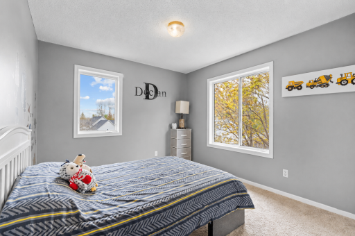 Well-sized bedroom with a cozy feel, large window, and neutral tones throughout.