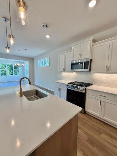 Photo of actual home. Brushed gold kitchen faucet and hardware give the space a luxurious pop of color and warmth!
