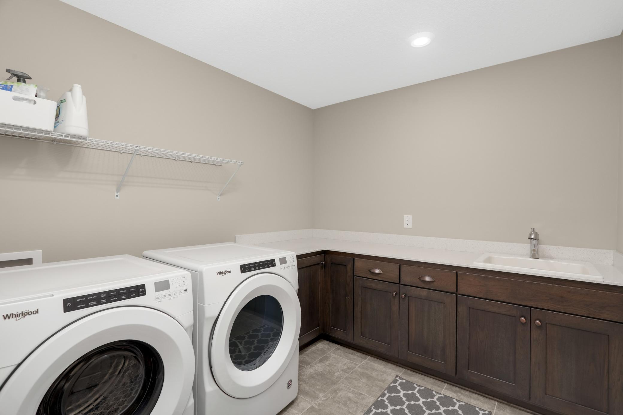 Laundry room has terrific cabinet storage space and a utility sink.