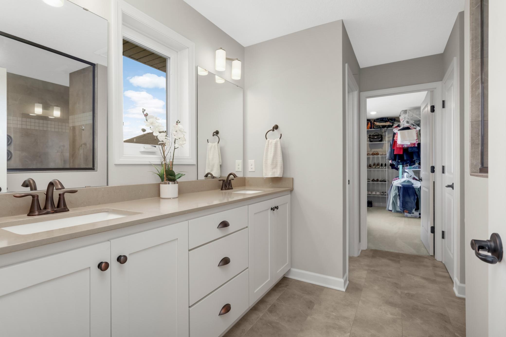Primary bathroom has a dual sink vanity, tiled walk-in shower, and TWO large walk-in closets.