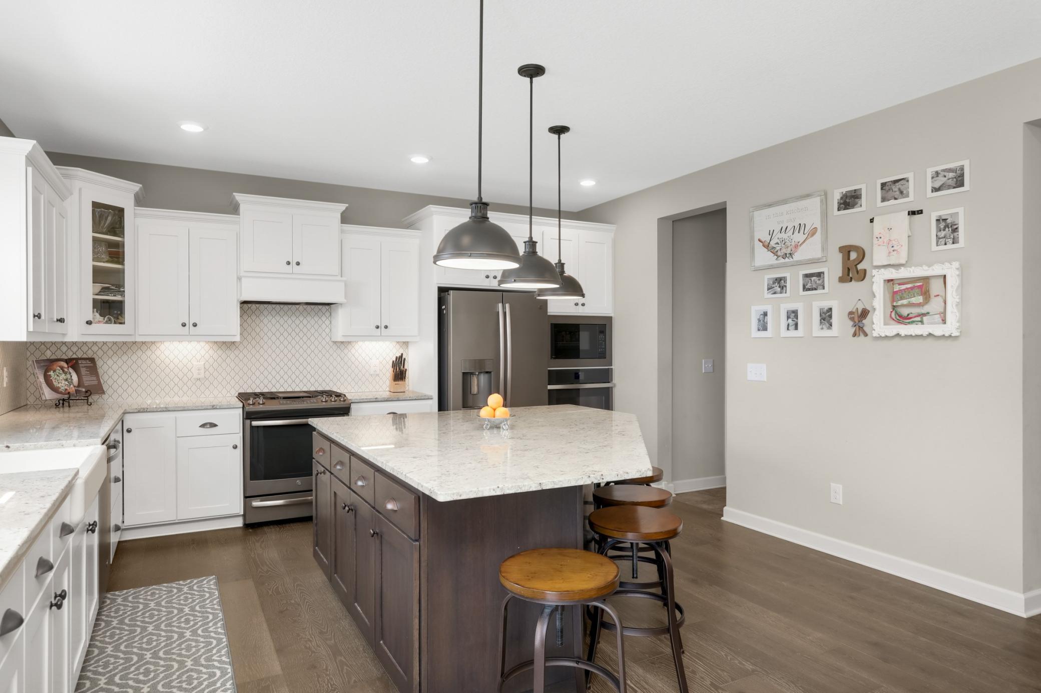 This high end kitchen has a wood hood, tile backsplash, slate appliances, and stone counters.