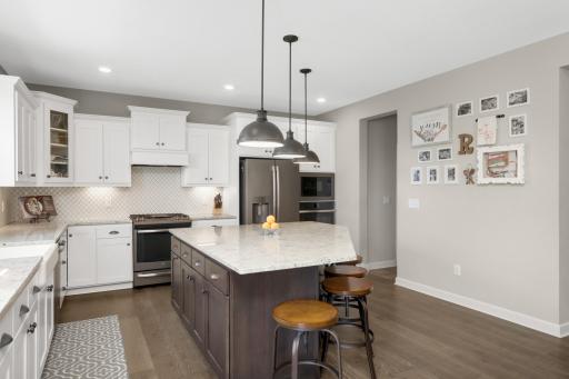 This high end kitchen has a wood hood, tile backsplash, slate appliances, and stone counters.