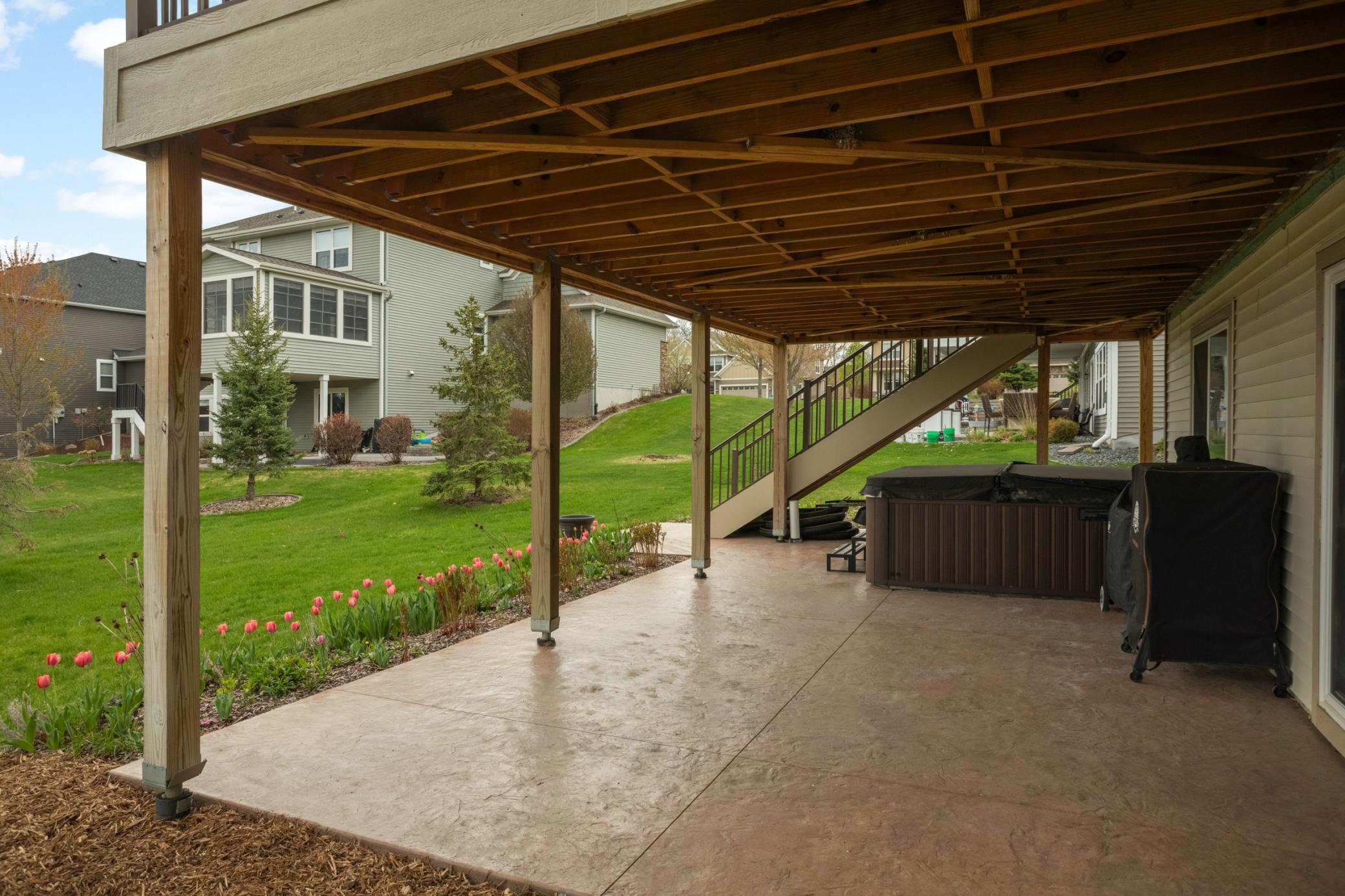 Concrete lower patio. Below the main deck, the under-decking system provides a shaded, rain-protected area.