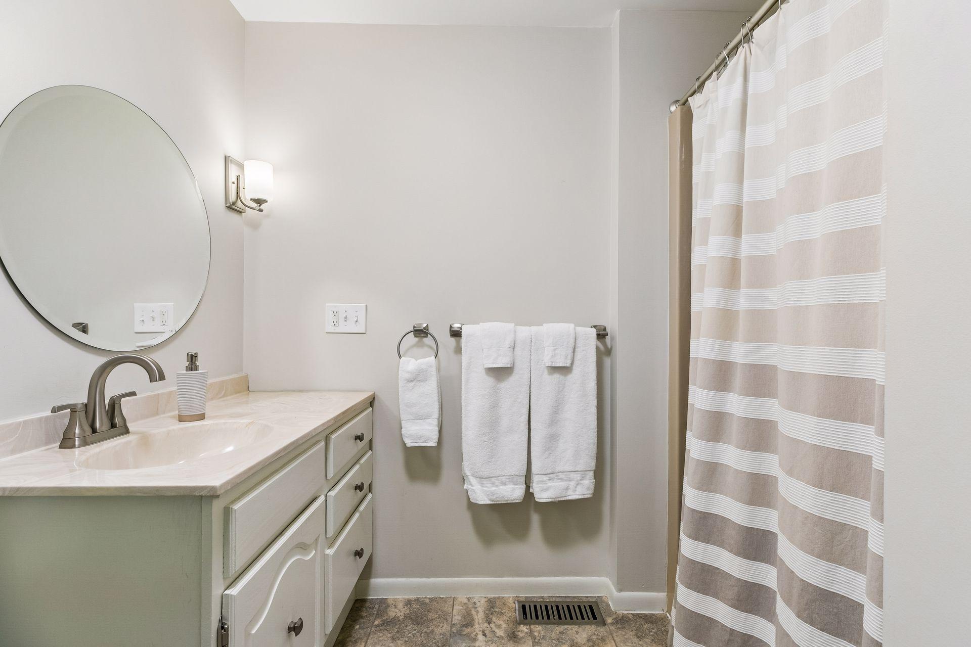Well appointed primary 3/4 ensuite bath with tile flooring, walk-in shower stall, and vanity sink.