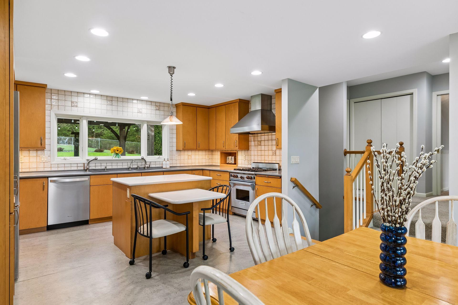 Kitchen featuring custom cabinetry, Corian countertops, and a tile backsplash, highlighted by recessed lighting and durable linoleum flooring.