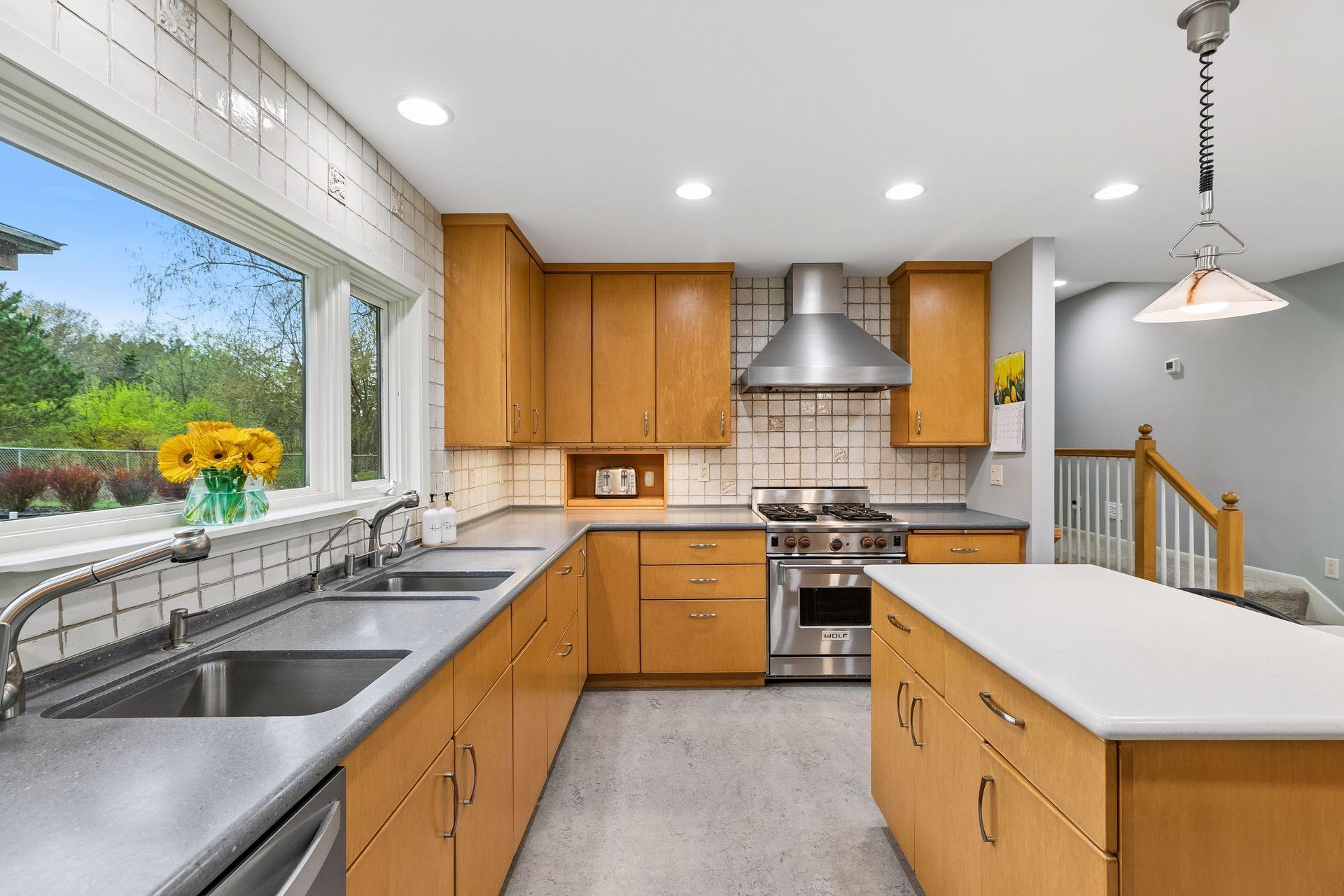 Another angle showcasing a large window over a generous double sink, filling the kitchen with natural light and enhancing the functional layout.