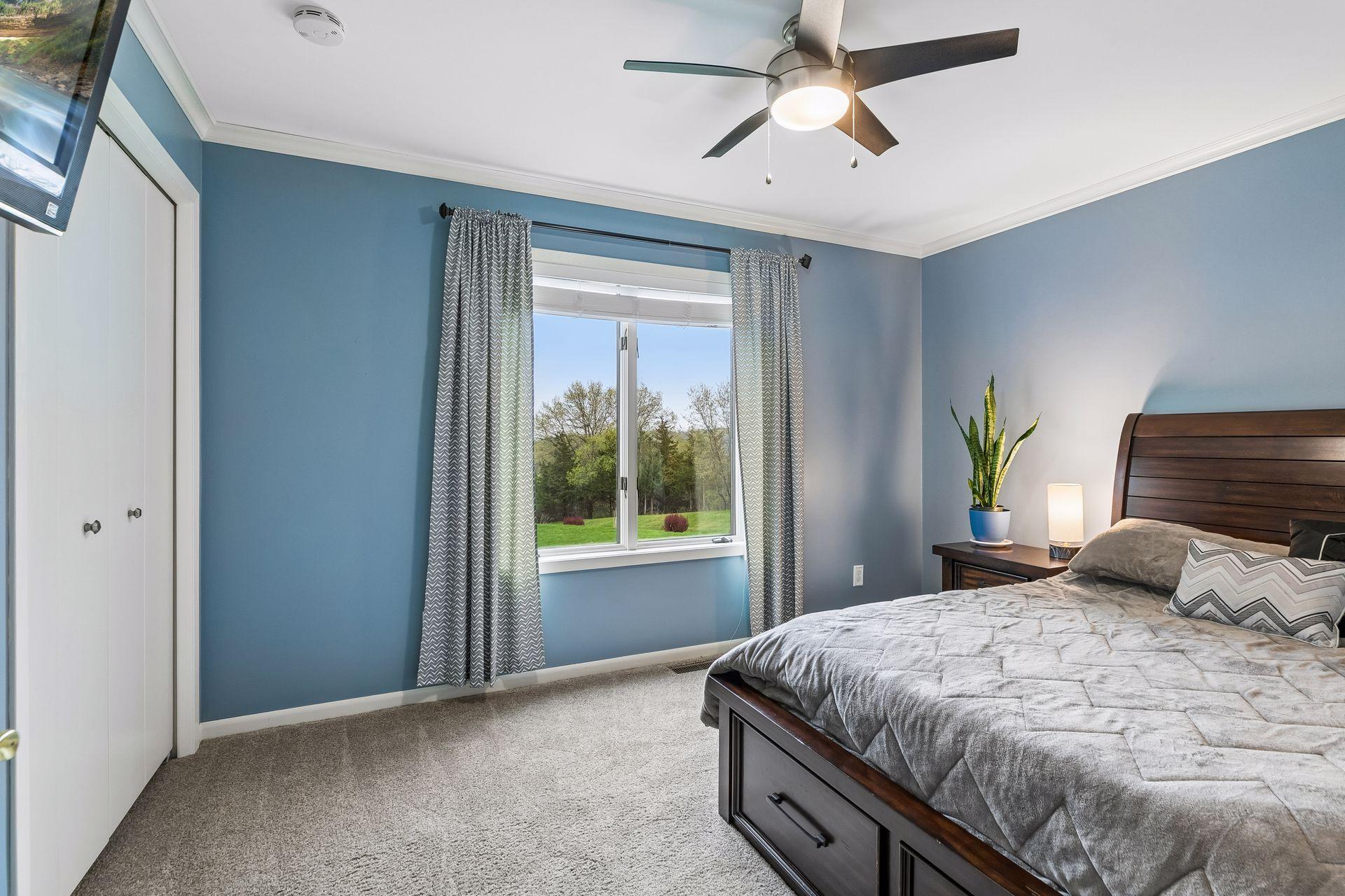 Inviting first of three main level bedrooms with cozy carpet, ceiling fan with light, and a double window enhancing natural light and atmosphere.