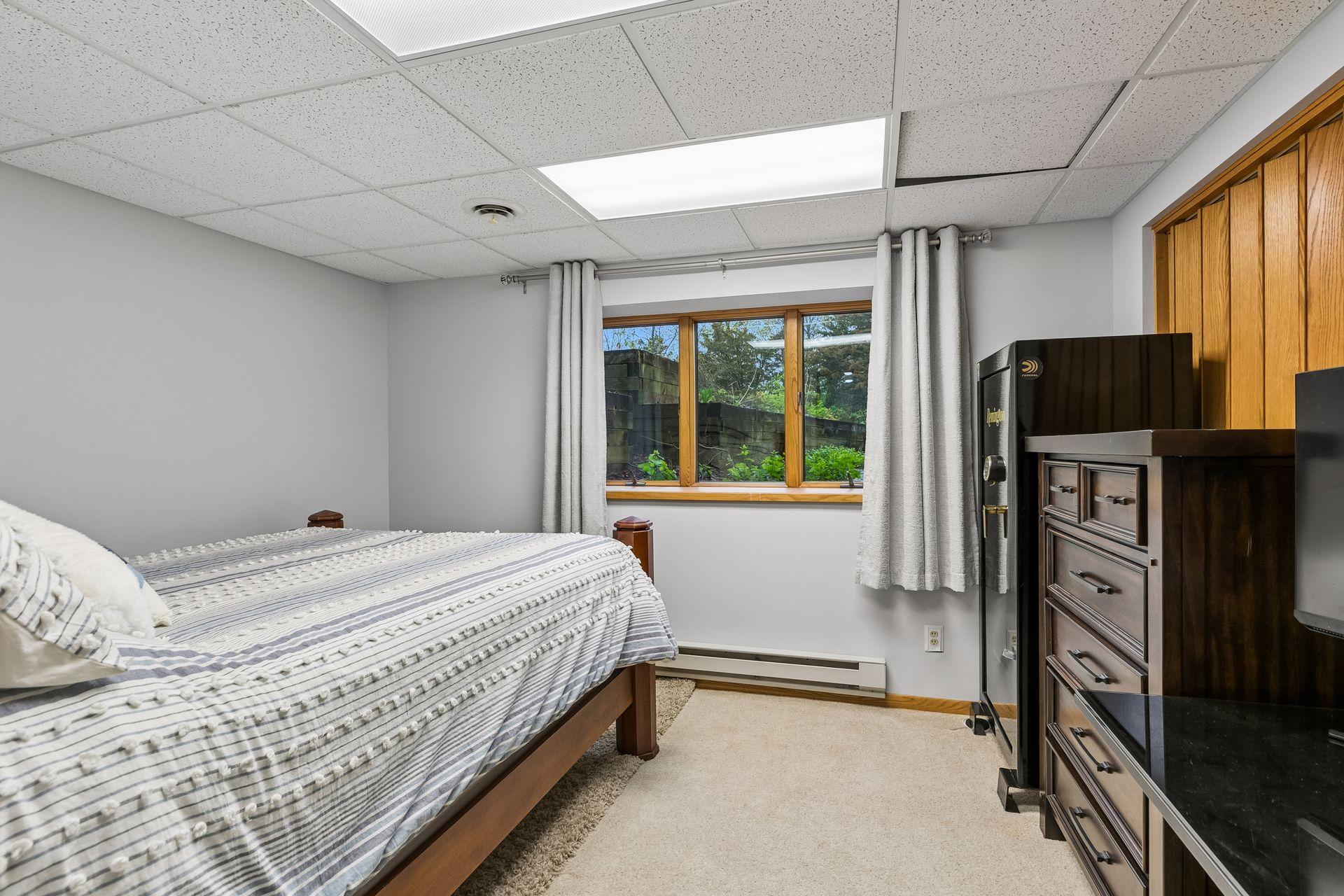 Versatile lower level bedroom or flex space with carpet floors and egress window