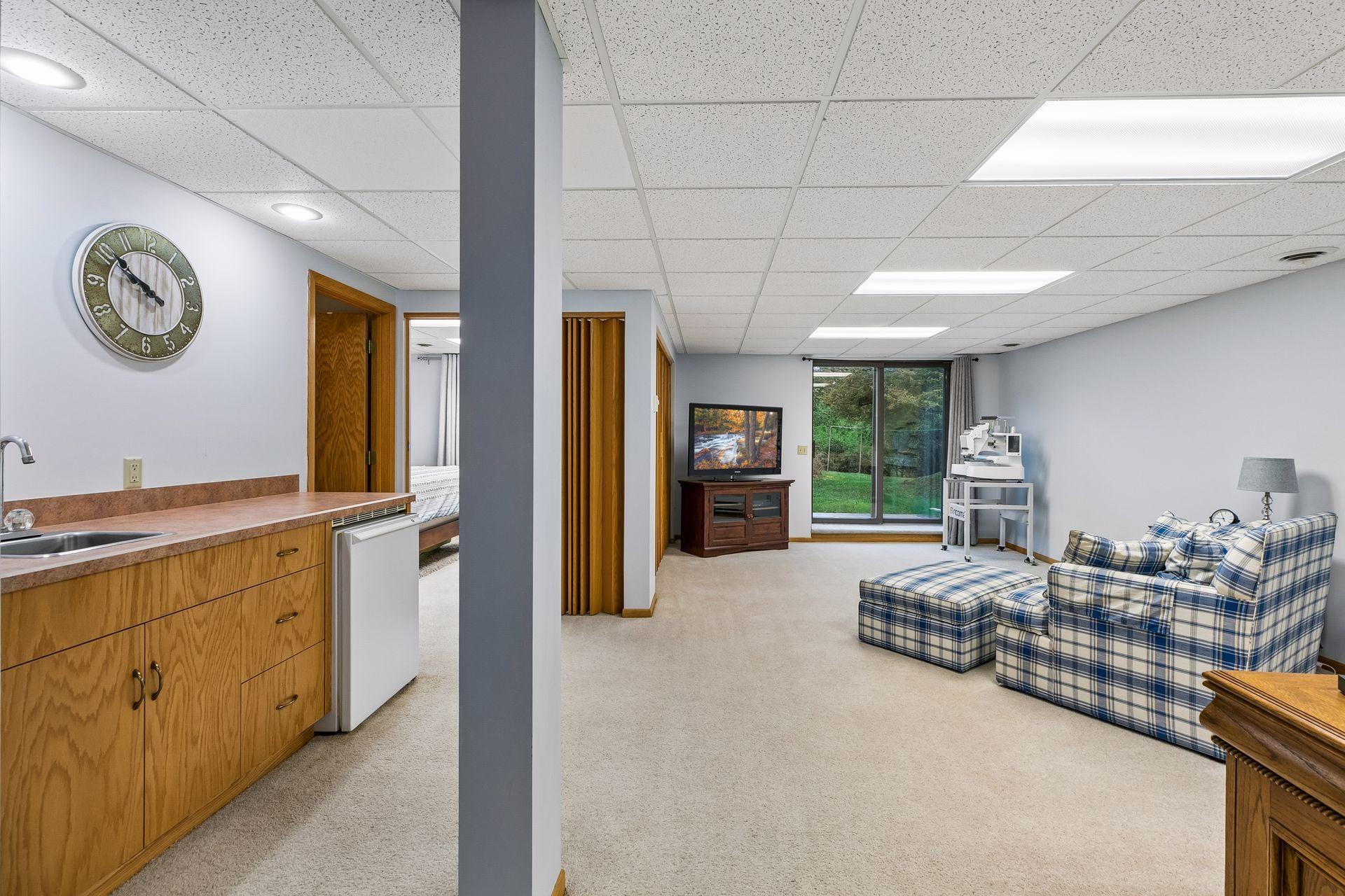 Lower level family room offering carpet flooring, recessed lighting, a wet bar with fridge, and double doors that open to the side yard for easy indoor/outdoor living.