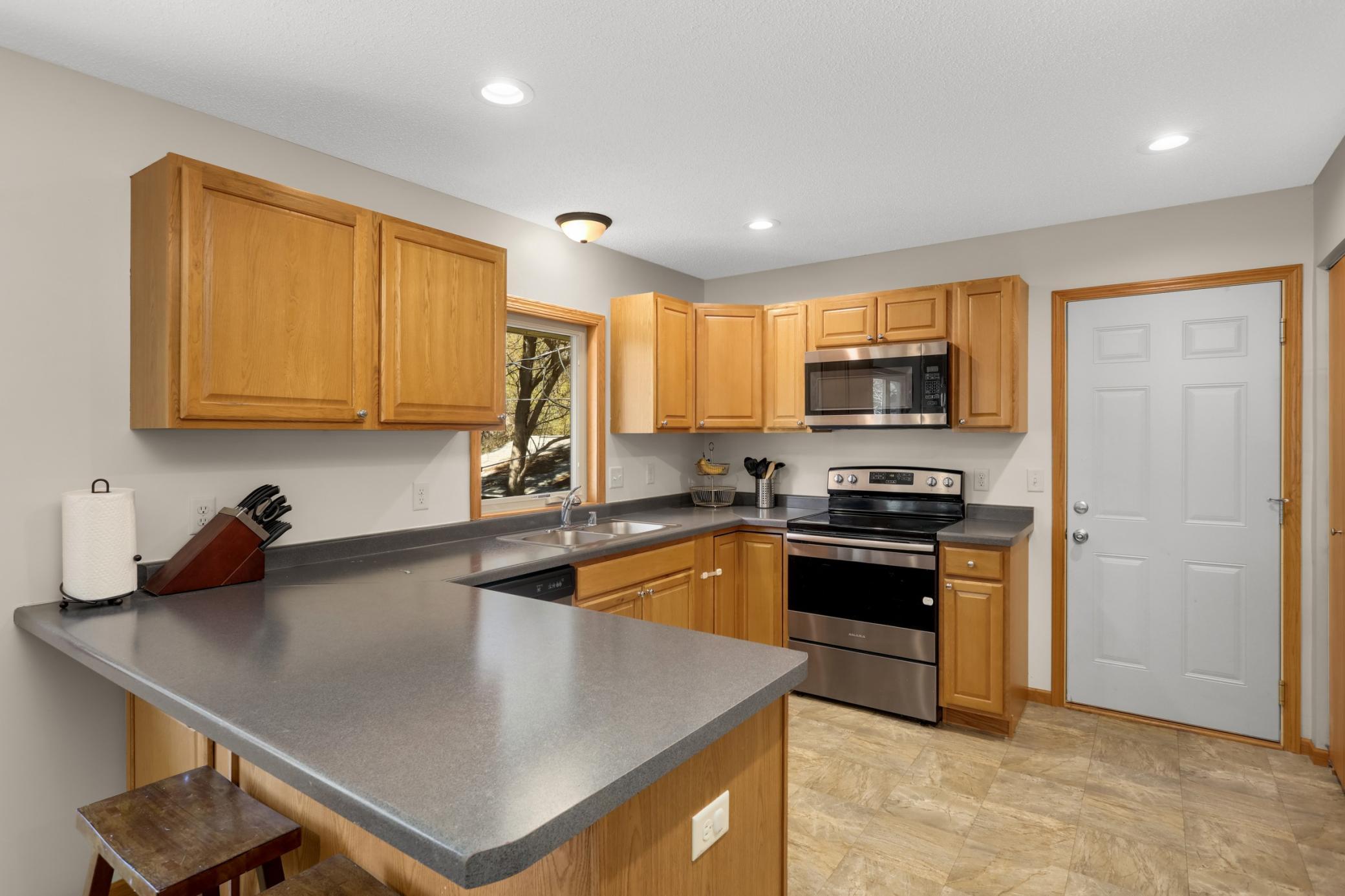 Large eat in kitchen with stainless steel appliances and updated flooring.