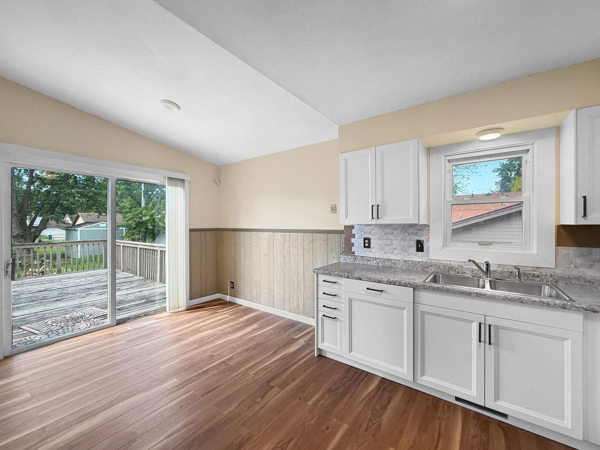 New flooring extends to the informal dining room off the kitchen. Sliding patio door opens to a large deck
