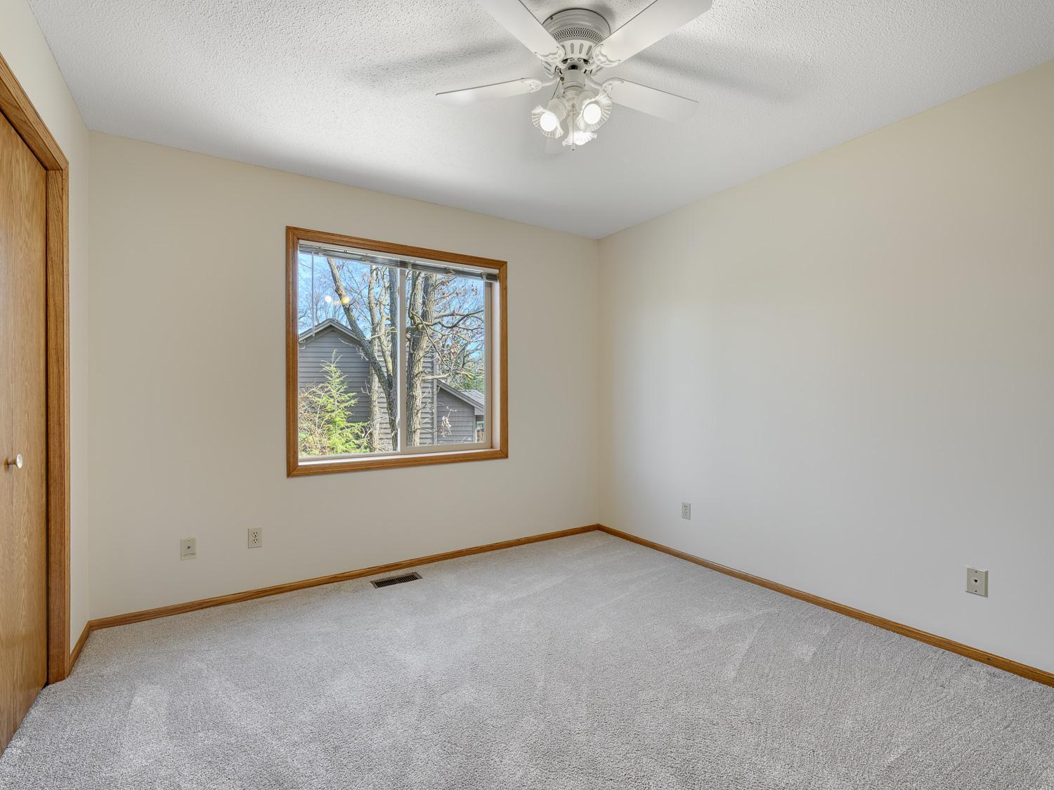 Second upper level bedroom features plush carpeting, neutral colors, and a ceiling fan.